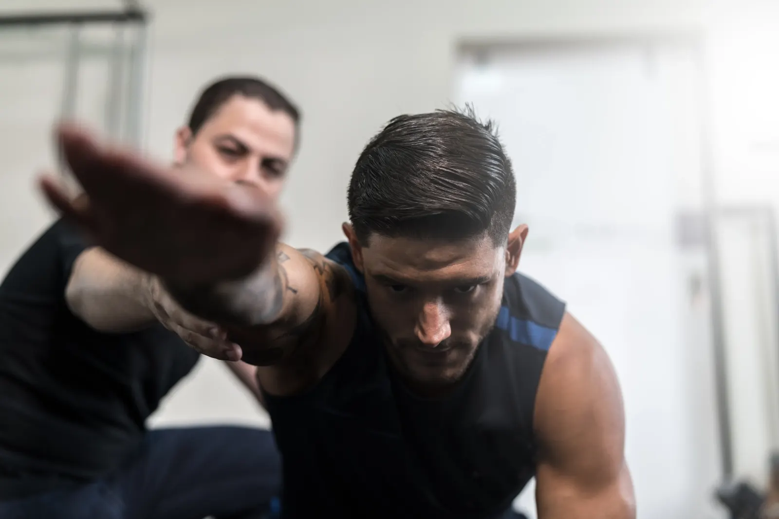 Trainer guiding a focused male athlete through a recovery and conditioning exercise indoors