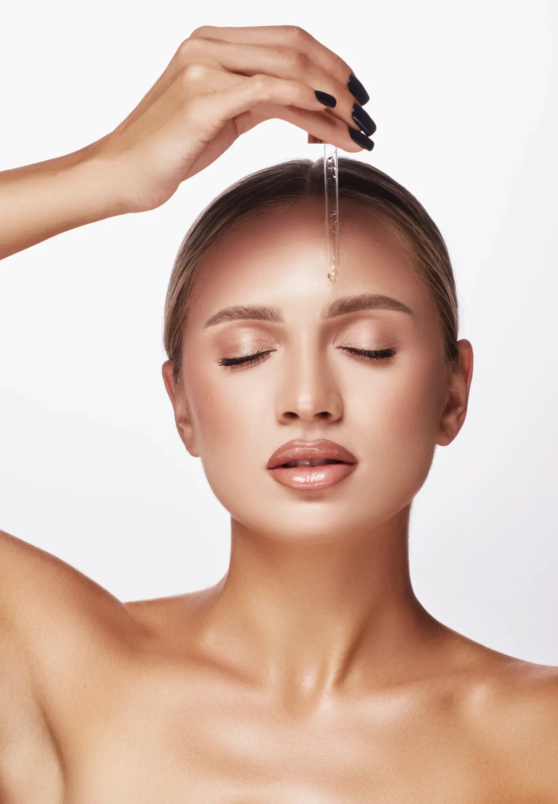 Woman with radiant skin applying a serum dropper to her forehead, reflecting a glutathione glow