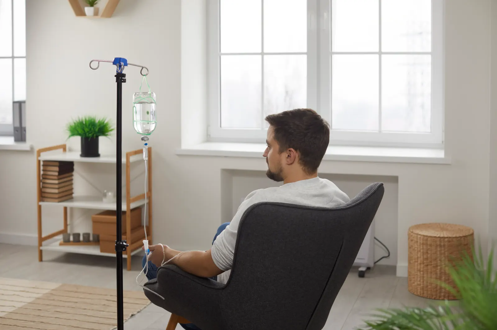Man relaxing in an armchair beside an IV drip stand during hangover recovery treatment in Westchester County