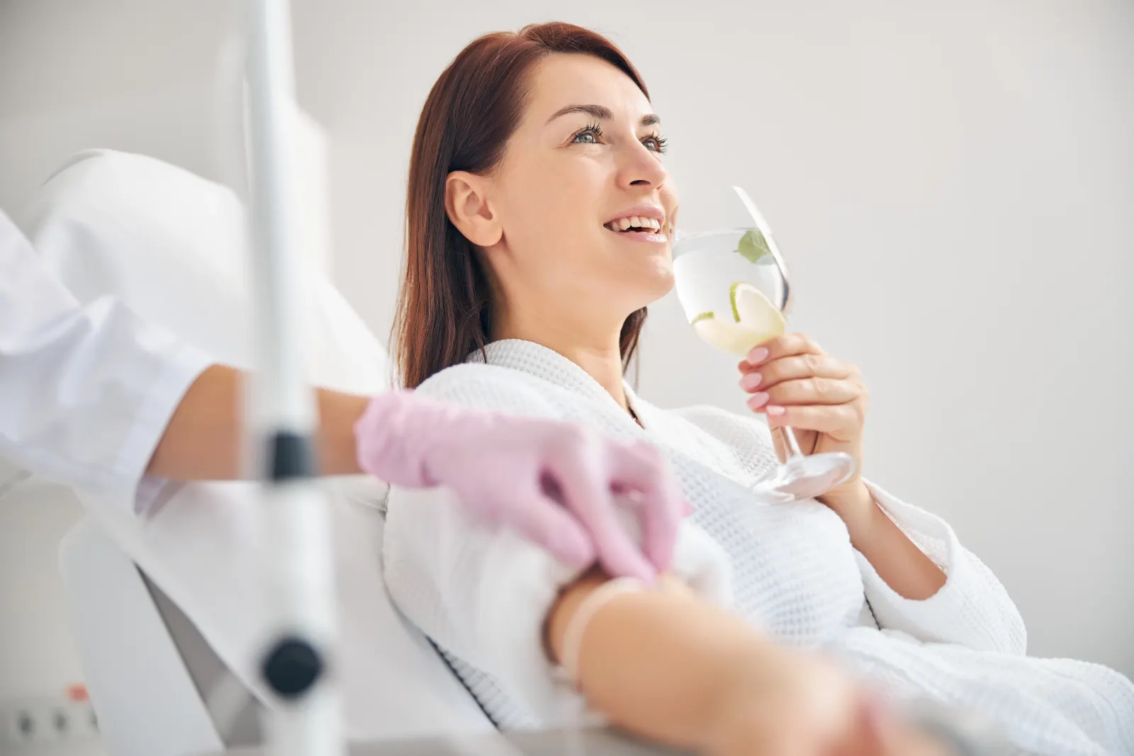 Woman in a robe sipping infused water during a Myers IV therapy session in New Rochelle