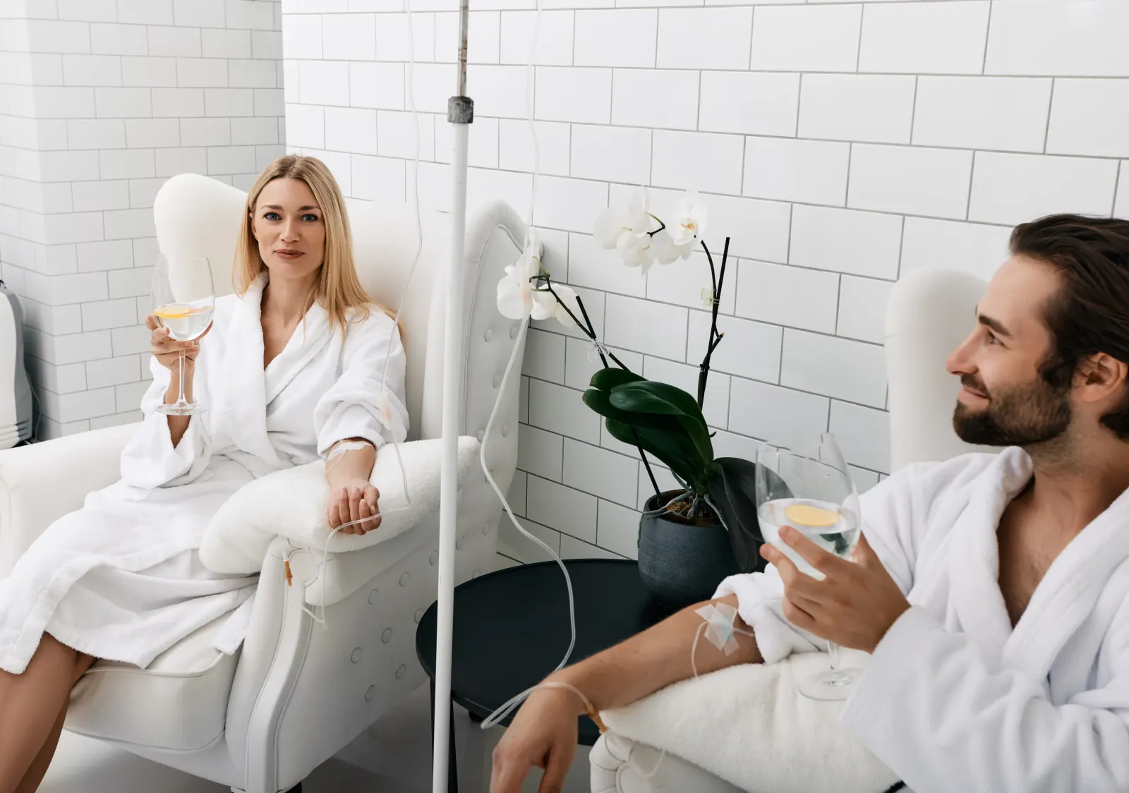 Couple in robes relaxing with drinks during side-by-side Myers IV therapy drips in Westchester County